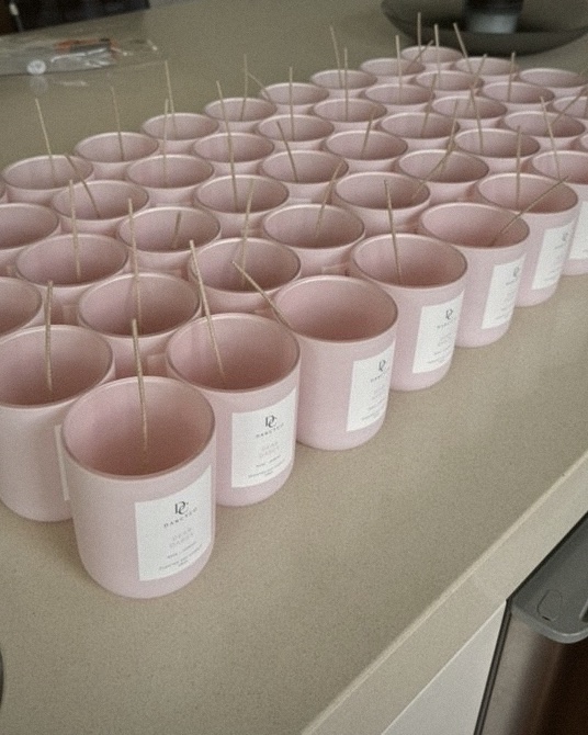 Rows of pink Dear Darcy jars with wicks, ready to pour